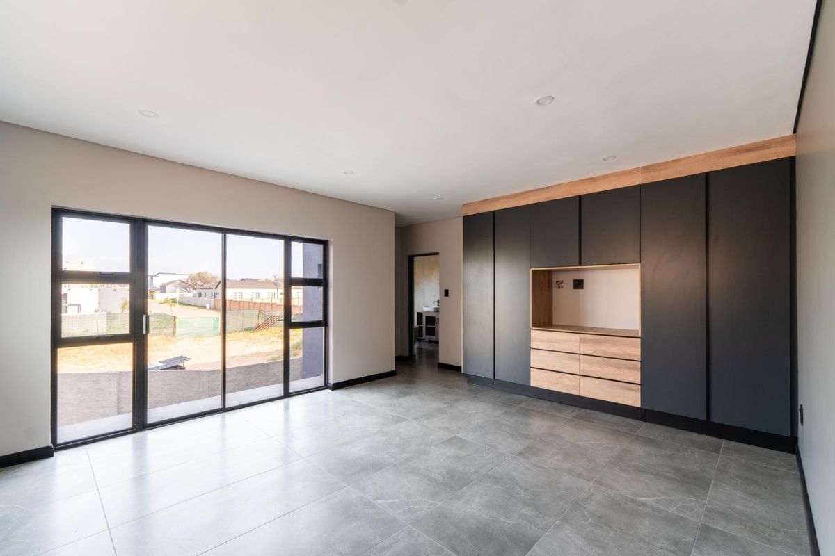 Modern bedroom featuring large sliding glass doors, sleek built-in cabinetry with integrated shelving, and contemporary grey floor tiles.
