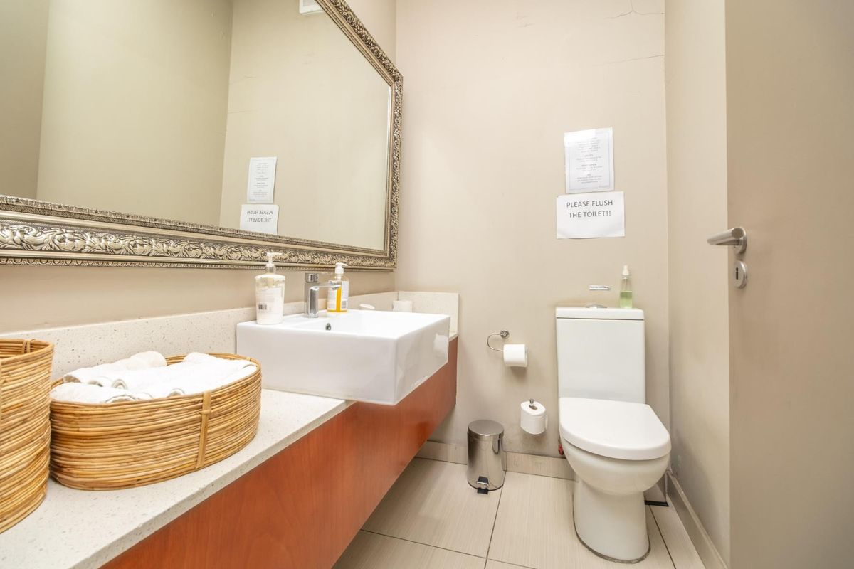 A functional bathroom featuring a modern vessel sink, stone countertop, vanity cabinet, large framed mirror, and a standard toilet.