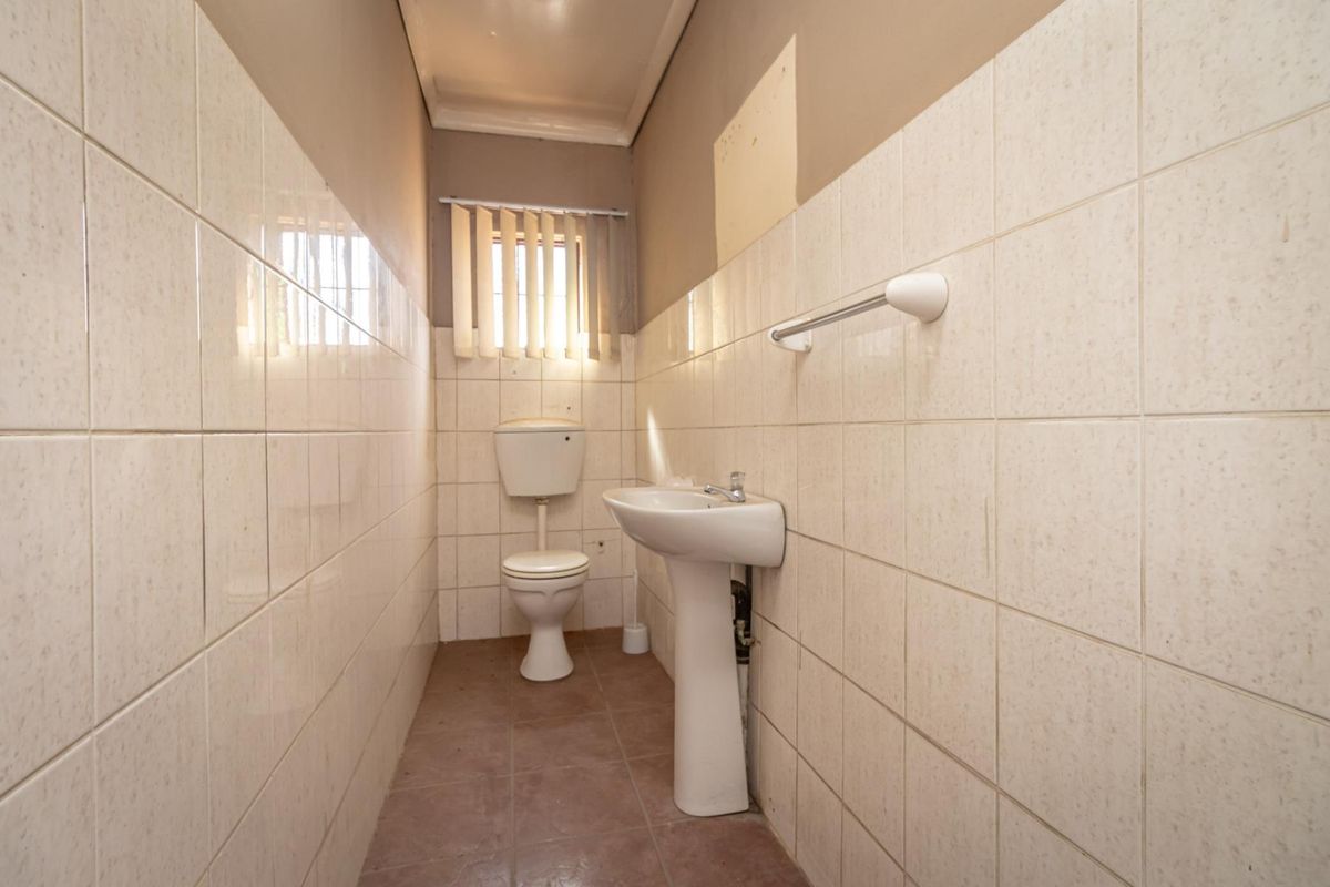 A compact commercial restroom featuring a pedestal basin, standard toilet, and tiled wall finishes.