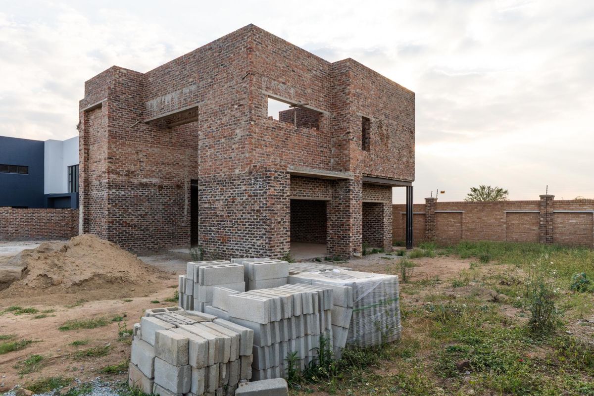 A double-story residential property currently under construction, featuring exposed brickwork and an unfinished exterior structure on a large plot.
