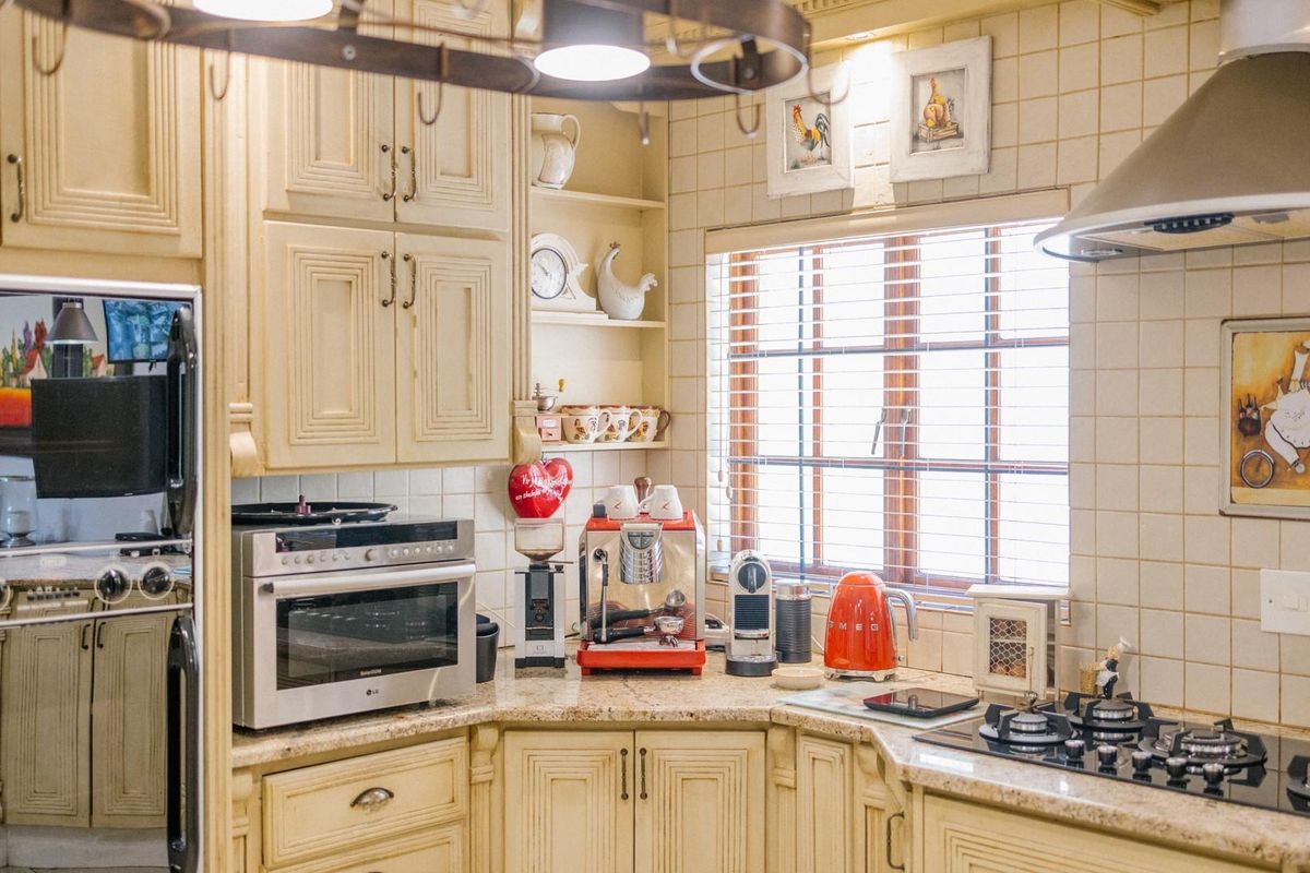 A traditional kitchen featuring cream-colored cabinetry, granite countertops, a built-in oven, and a gas hob with a stainless steel extractor fan.