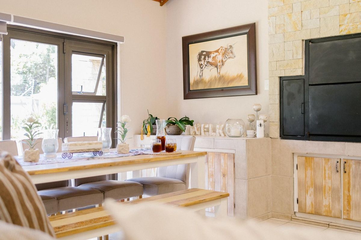 A cozy living area featuring a built-in fireplace with stone cladding, tiled flooring, and large glass doors providing natural light and garden access.