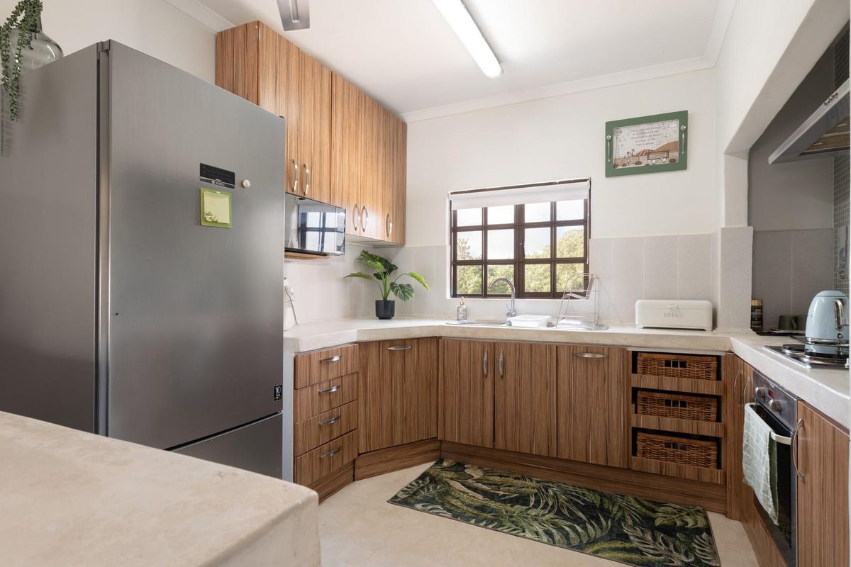 A functional kitchen featuring wood-grain cabinetry, stone-look countertops, a built-in oven, and a stainless steel sink with a window view.