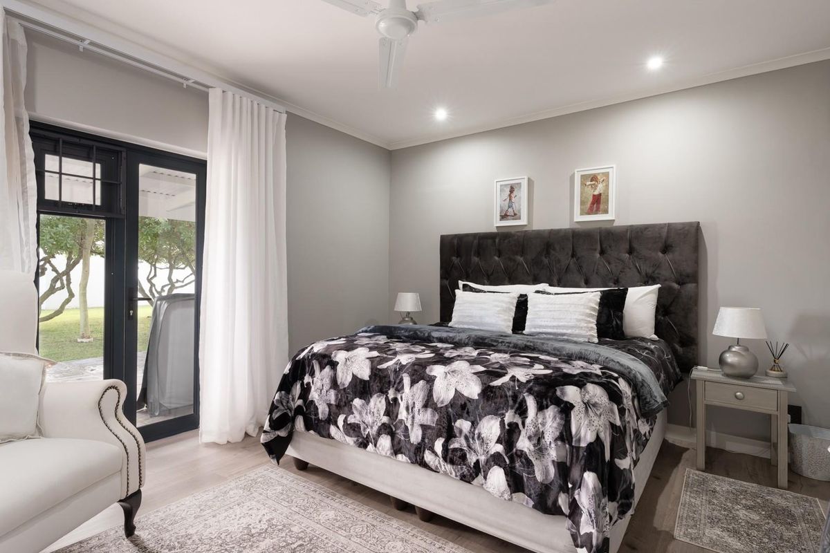 A well-maintained bedroom featuring neutral wall tones, a ceiling fan, and direct access to the garden through a glass-paned door.