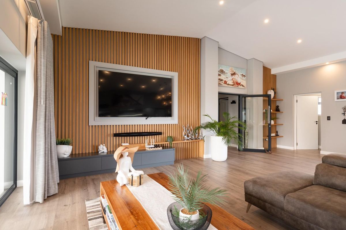 Modern living room featuring a striking timber slat feature wall, built-in cabinetry, and large sliding glass doors providing seamless access to the outdoors.