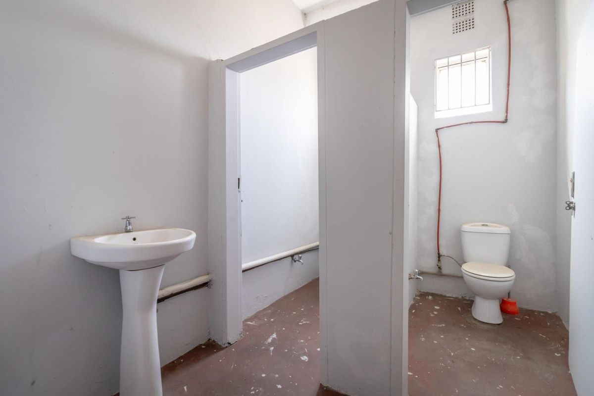 A basic, unfinished bathroom facility featuring a pedestal basin and a standard toilet, requiring cosmetic updates and finishing touches.