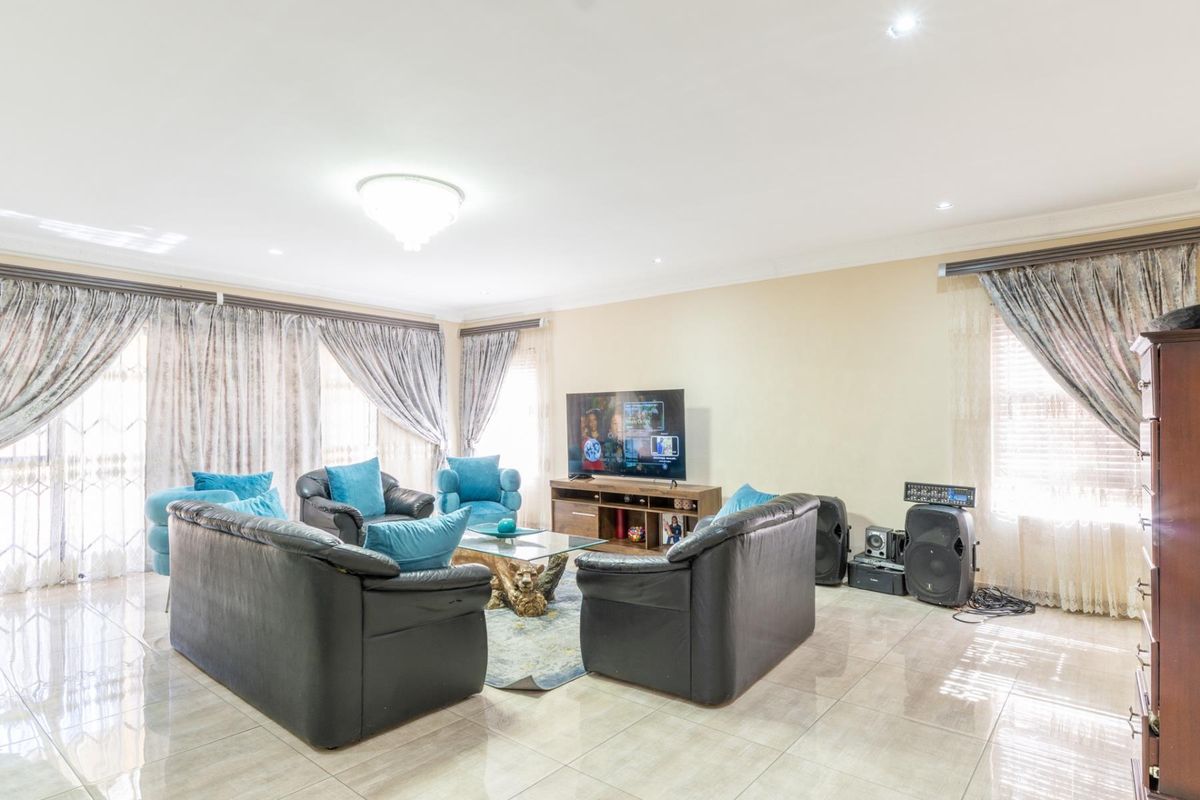 Spacious living room featuring large format floor tiles, recessed downlighting, and expansive windows with curtain treatments.