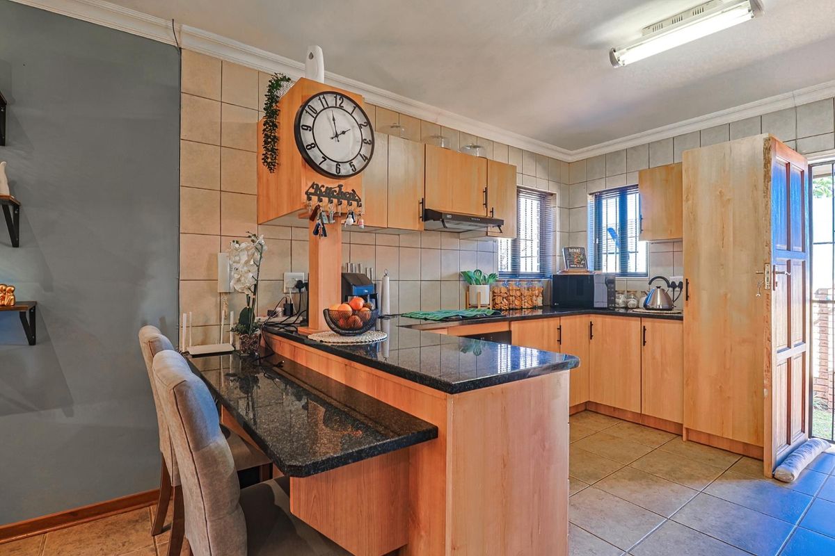 Functional kitchen featuring wooden cabinetry, granite countertops, a breakfast bar, and tiled finishes, offering a practical layout for daily meal preparation.