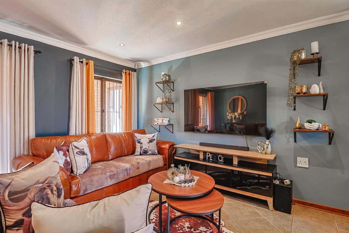 A cozy living room featuring tiled flooring, crown molding, and recessed downlights, creating a comfortable and well-maintained space.
