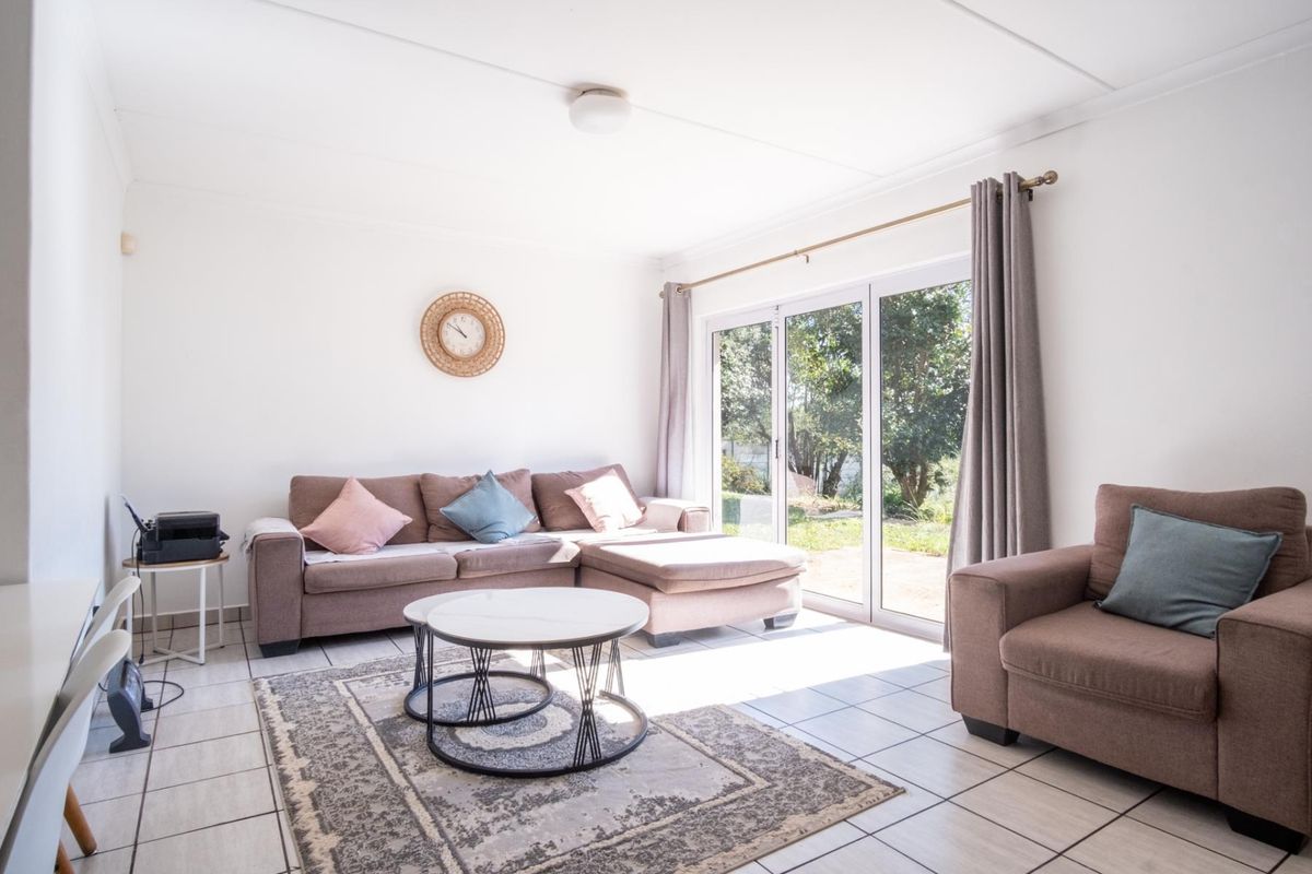 A bright living room featuring tiled flooring and large sliding glass doors that provide direct access to the garden area.