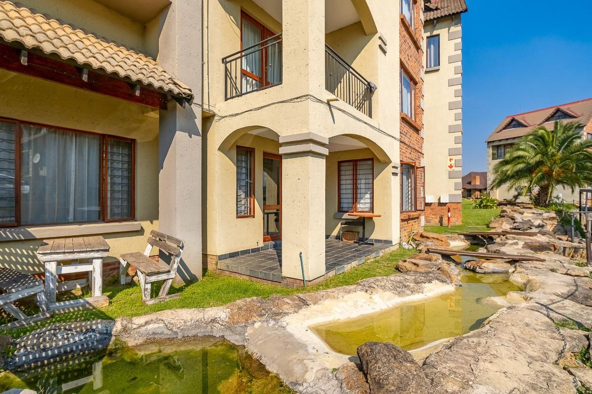Ground floor apartment featuring a private patio area overlooking a landscaped rock garden and water feature within a residential complex.