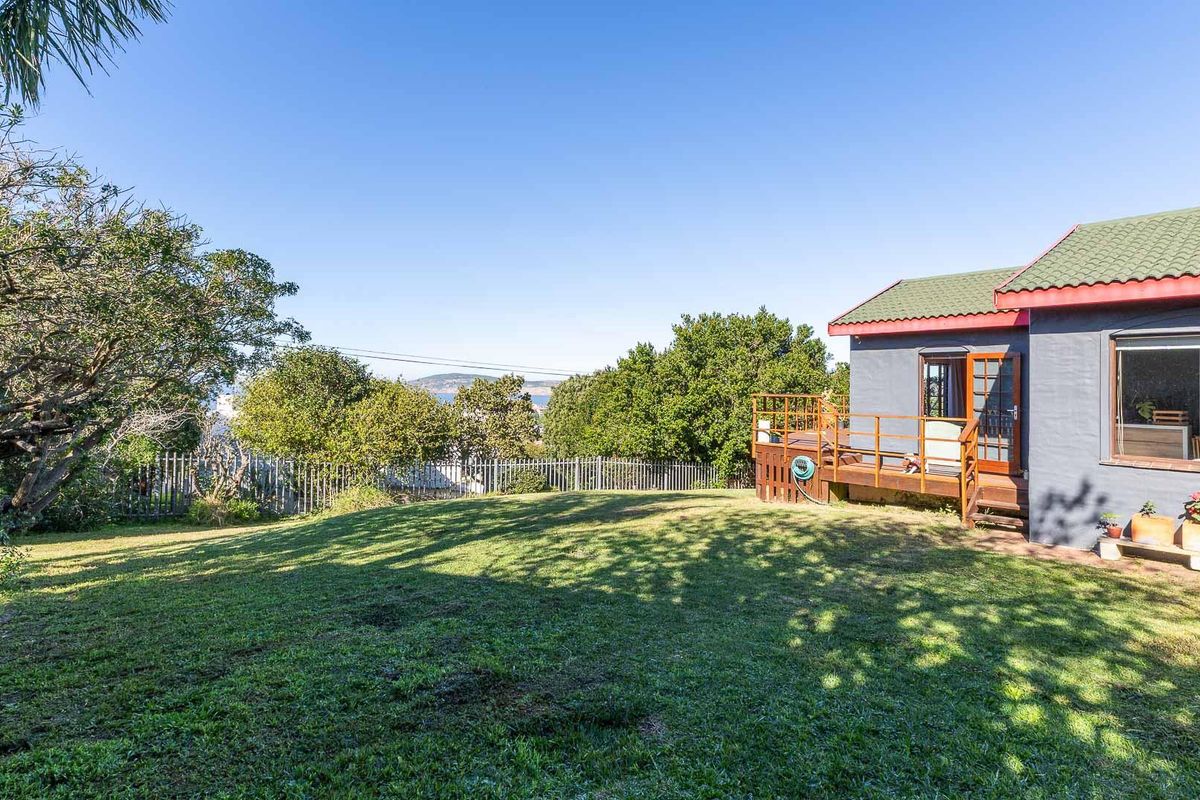 A spacious rear garden featuring a raised timber deck, green lawn, and established trees, providing a private outdoor space with a view.