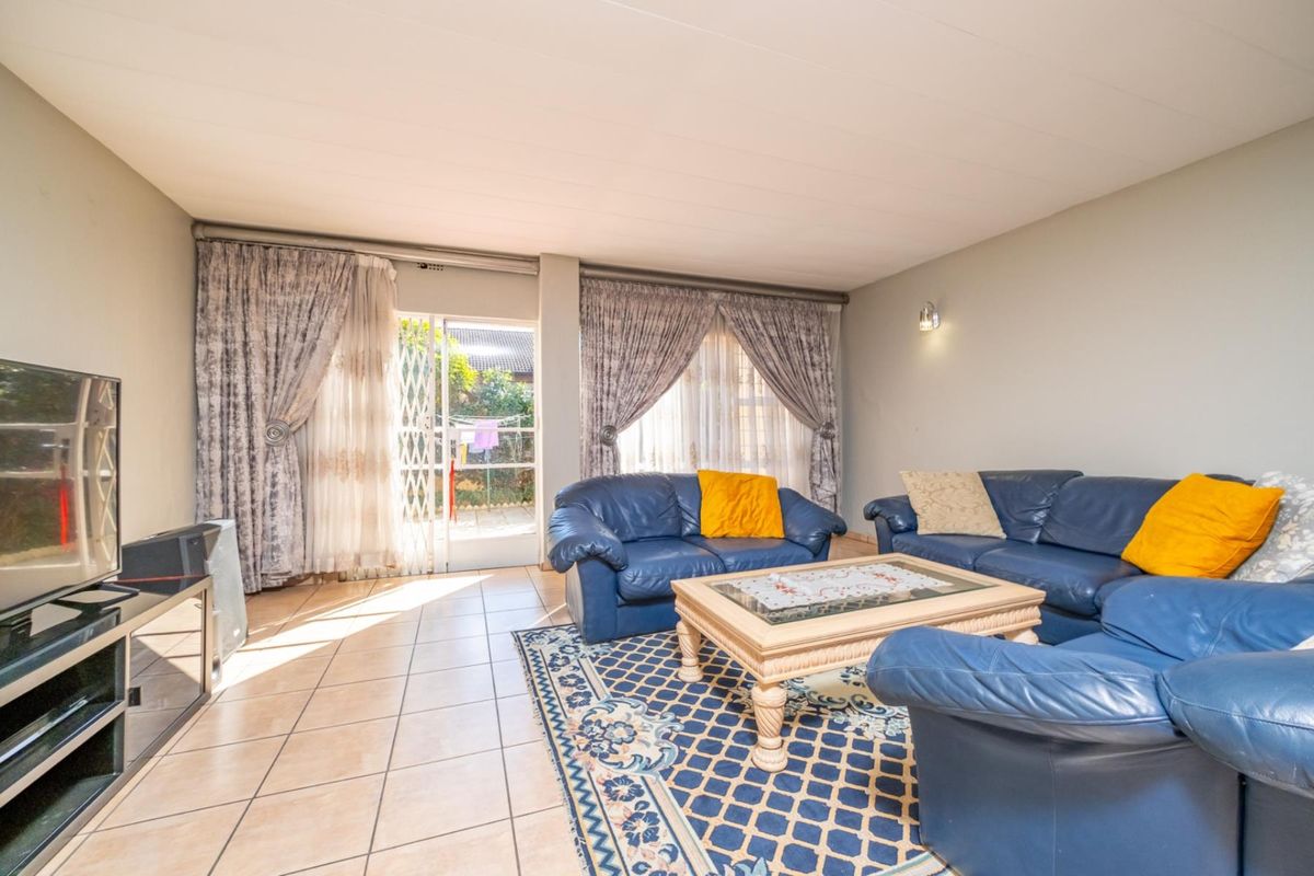 A spacious living room featuring tiled flooring and a sliding glass door providing direct access to the outdoor patio area.