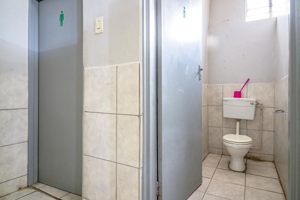 Commercial restroom facility featuring separate male and female access doors and a standard ceramic toilet suite with tiled walls and flooring.