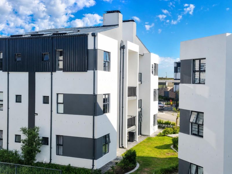 Modern multi-story apartment building exterior featuring a contemporary black and white facade with balconies and landscaped grounds.