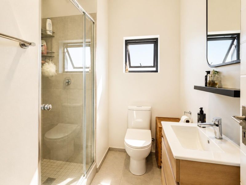 Modern bathroom featuring a glass-enclosed shower, a sleek vanity with an integrated basin, and neutral floor tiles.