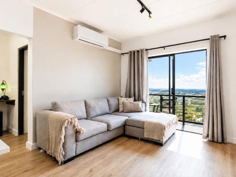 Modern living room featuring laminate flooring, air conditioning, and large sliding glass doors opening to a balcony with expansive scenic views.