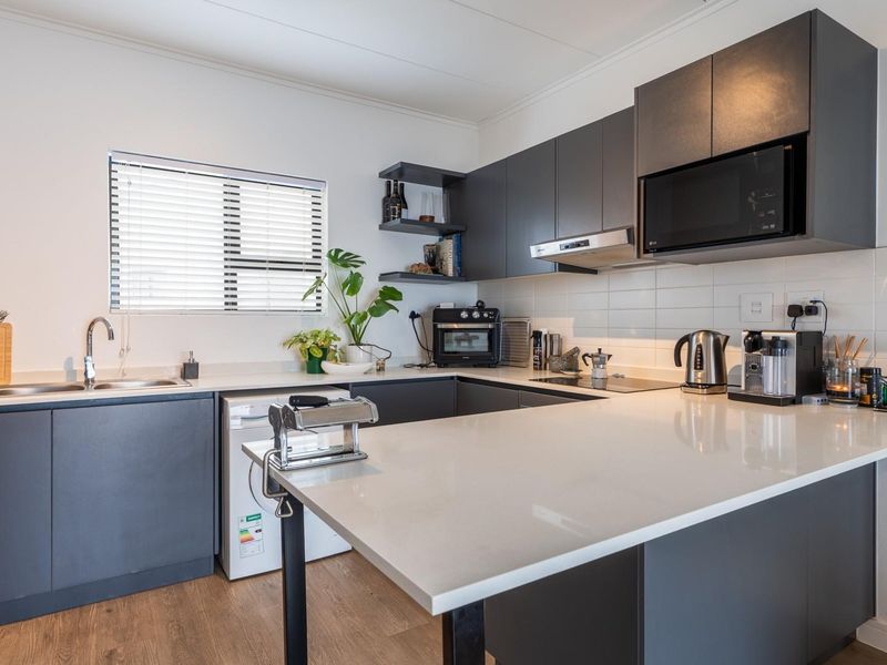 Modern kitchen featuring dark grey cabinetry, white quartz countertops, subway tile backsplash, and integrated appliances including a microwave and extractor fan.