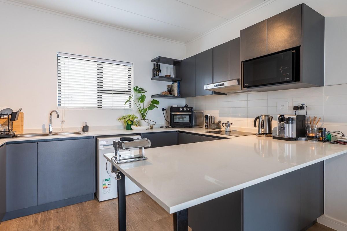 Modern kitchen featuring dark grey cabinetry, white quartz countertops, subway tile backsplash, and integrated appliances including a microwave and extractor fan.