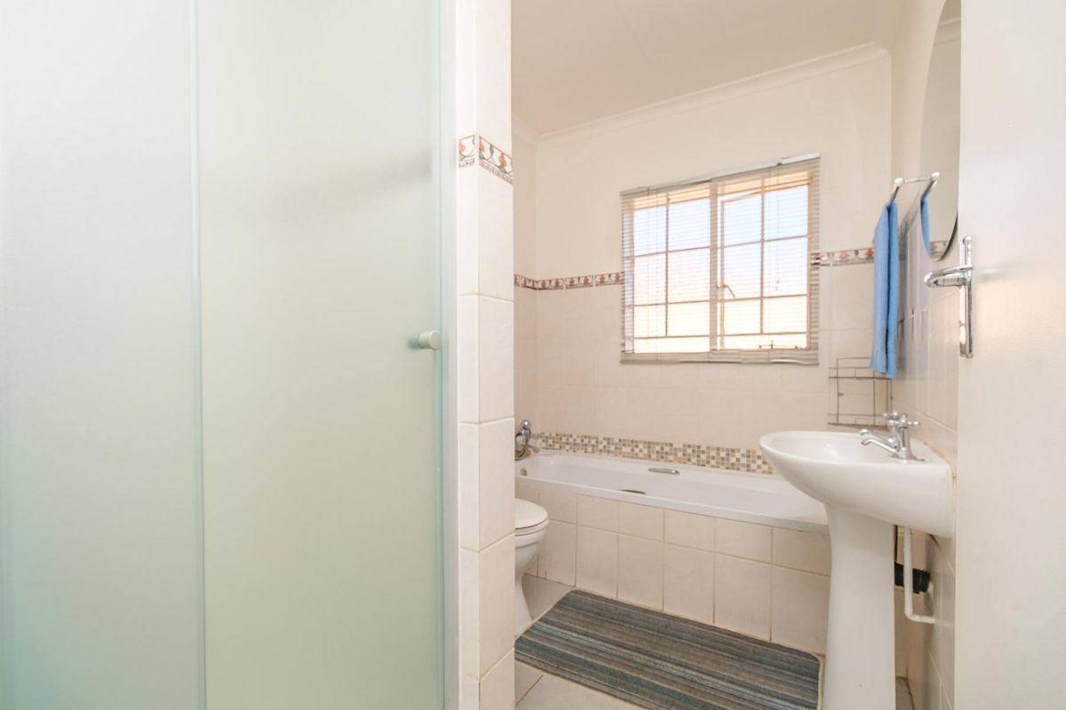 A functional bathroom featuring a pedestal basin, a built-in bathtub with tiled surround, and a separate shower enclosure.