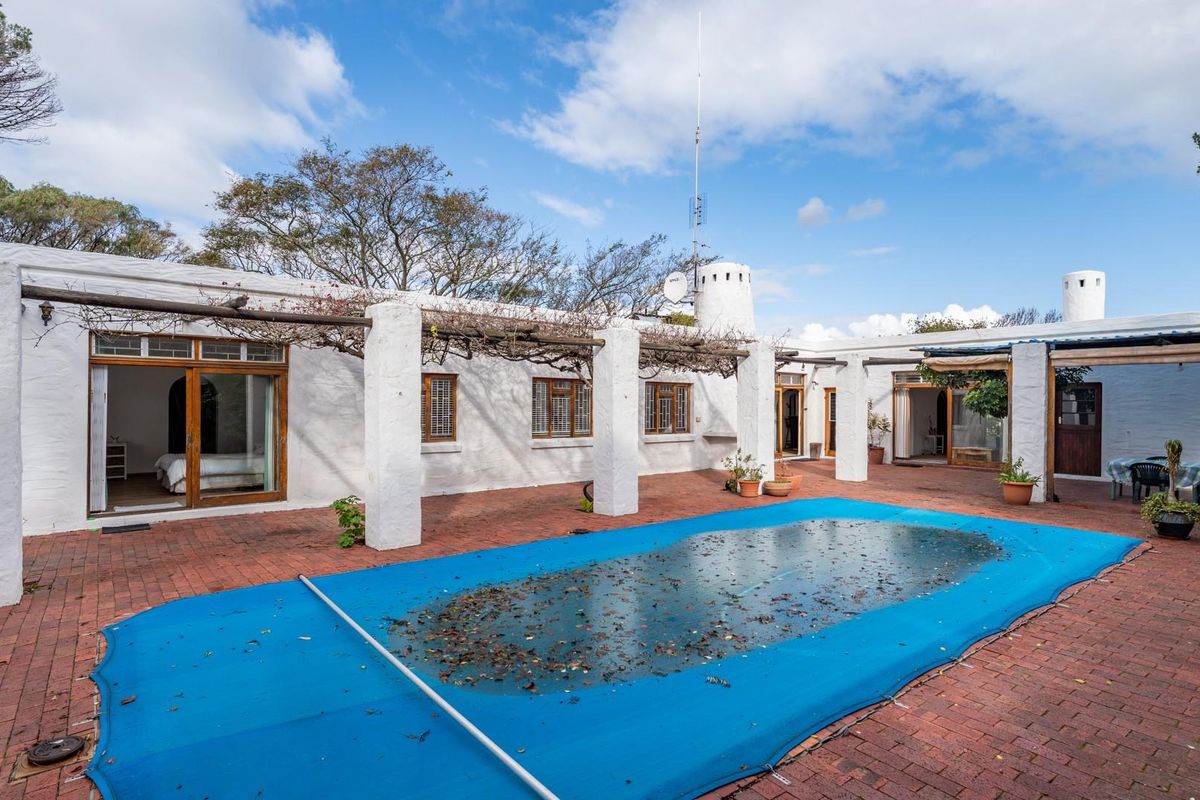 Spacious rear courtyard featuring a brick-paved patio, a covered pergola area, and a swimming pool with a protective cover.