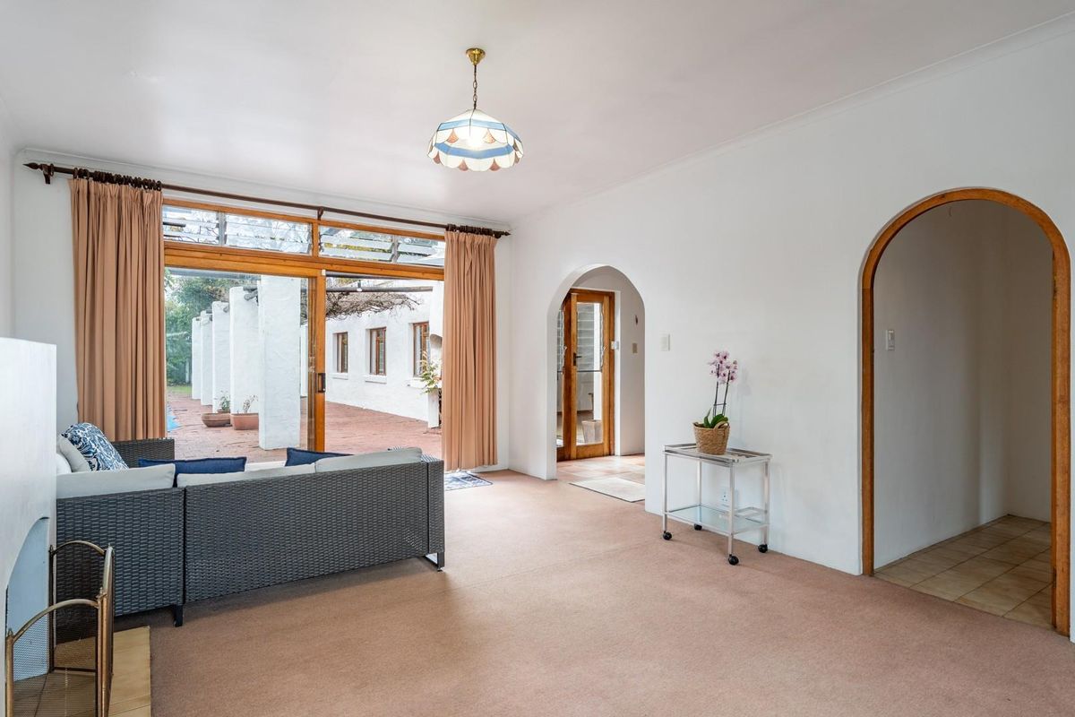 Spacious living room featuring arched doorways, neutral carpeting, and large sliding glass doors providing direct access to the outdoor patio area.