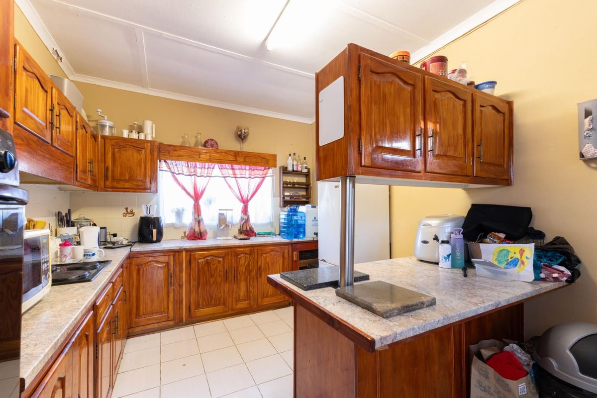 A functional kitchen featuring traditional wooden cabinetry, laminate countertops, a built-in hob, and tiled flooring, offering a classic layout with ample storage space.