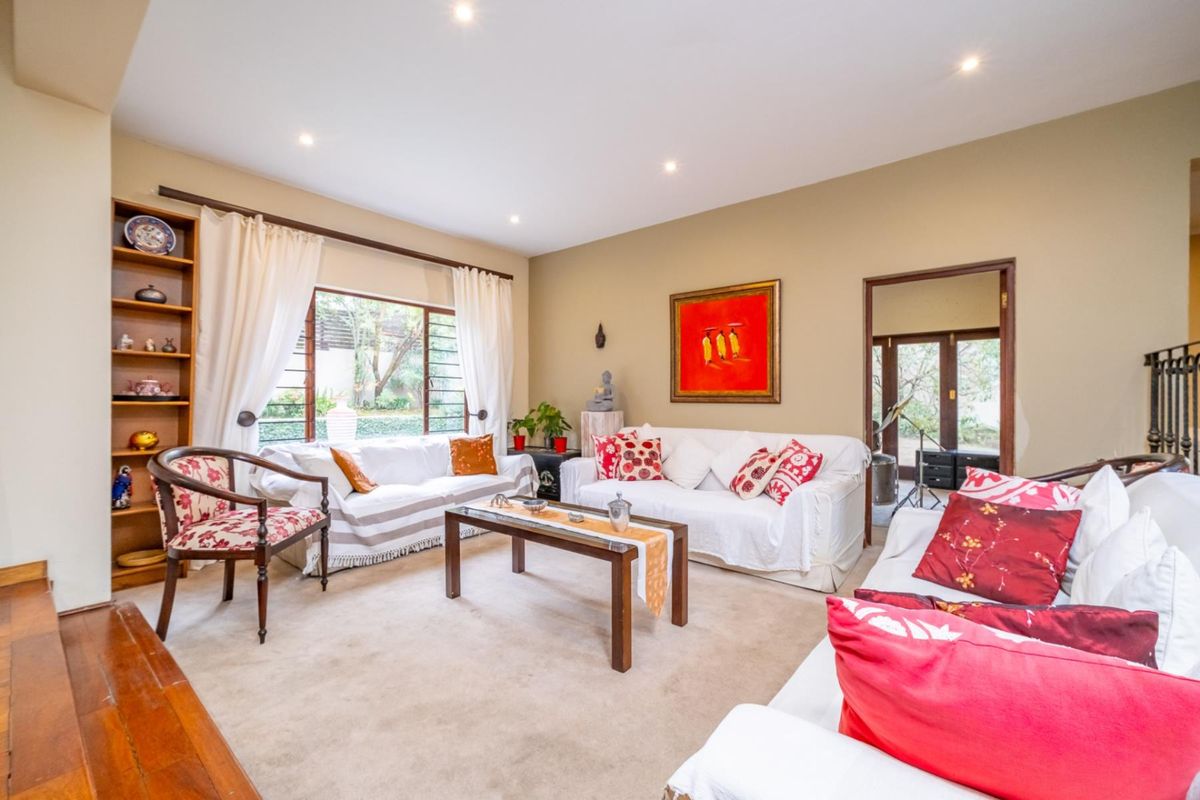 A comfortable living room featuring built-in shelving, recessed lighting, and large windows that provide natural light and views of the garden.