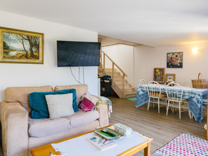 Open-plan living and dining area featuring laminate flooring and a wooden staircase leading to the upper level.