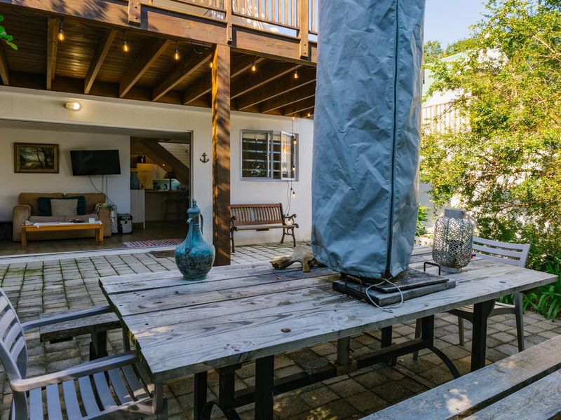 A spacious covered patio area featuring paved flooring, a wooden overhead deck, and seamless access to the interior living space through sliding glass doors.