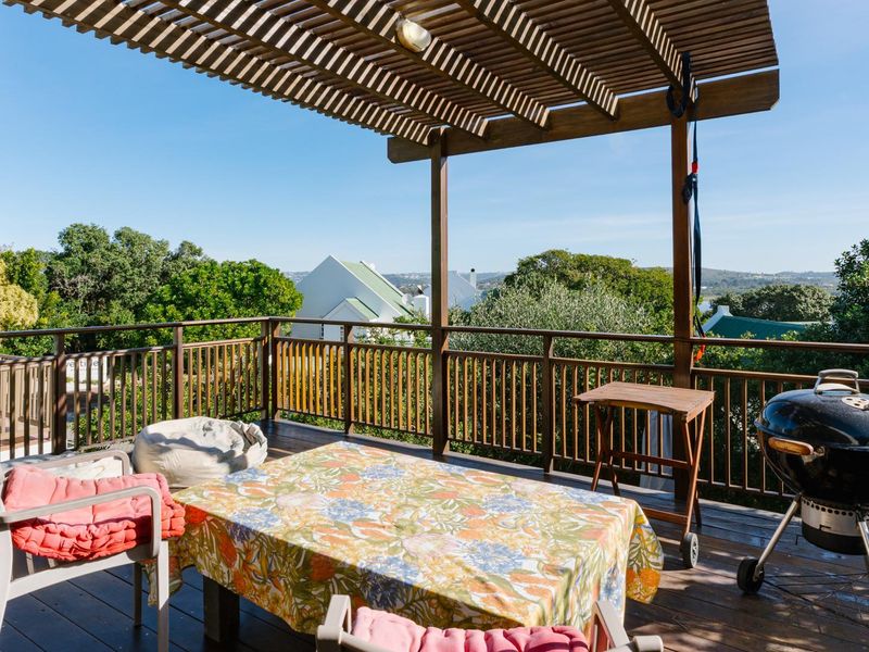 Elevated timber deck featuring a pergola and balustrade, offering an outdoor entertainment space with scenic views.