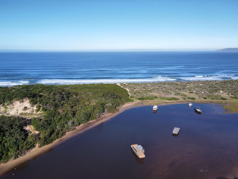An aerial view of the coastal estuary, dunes, and ocean, showcasing the natural landscape surrounding the property.