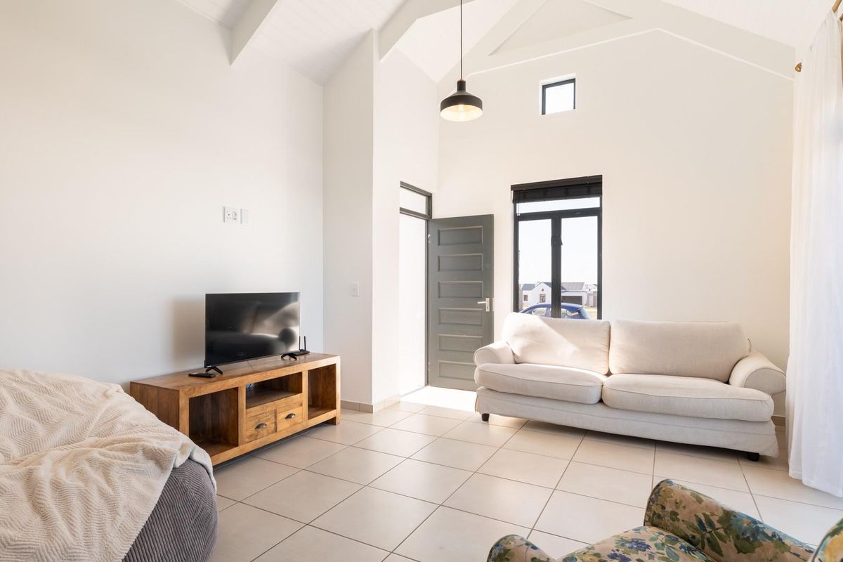 Bright living room featuring high vaulted ceilings, tiled flooring, and large windows providing ample natural light with direct access to the exterior.