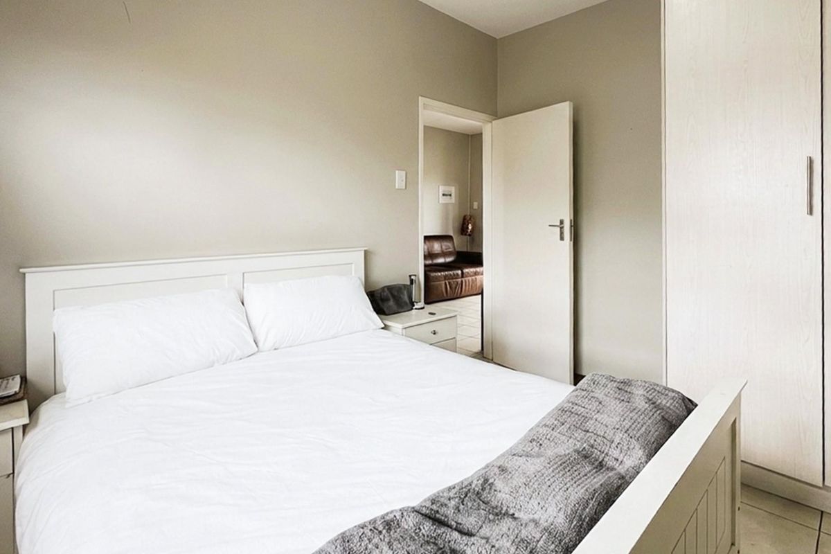 A well-lit bedroom featuring neutral wall tones, built-in cabinetry, and tiled flooring, offering a clean and functional living space.