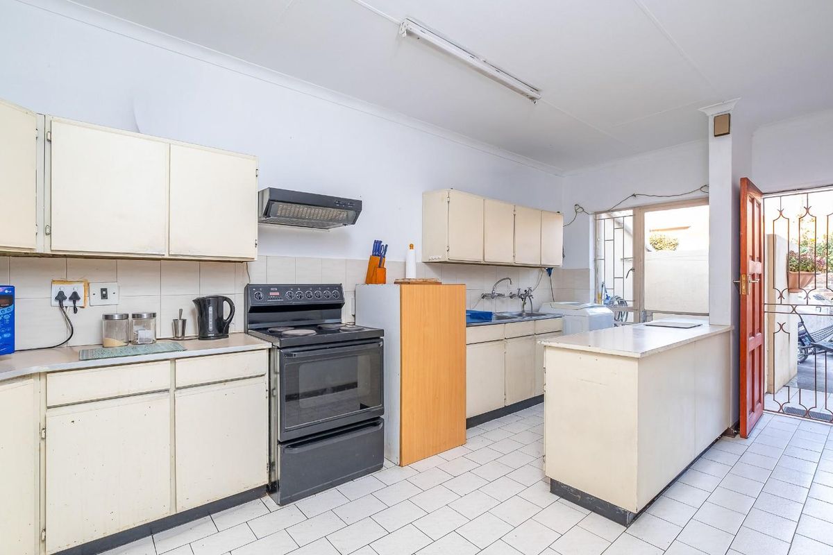 A functional kitchen featuring built-in cabinetry, a tiled backsplash, and direct access to the exterior through a security gate.