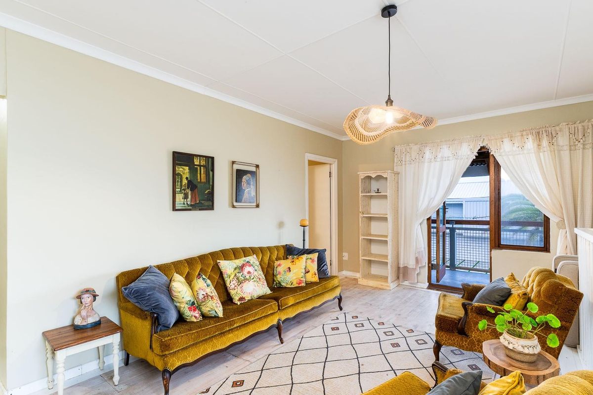 A bright living room featuring light-toned flooring, a pendant light fixture, and direct access to an outdoor balcony area.
