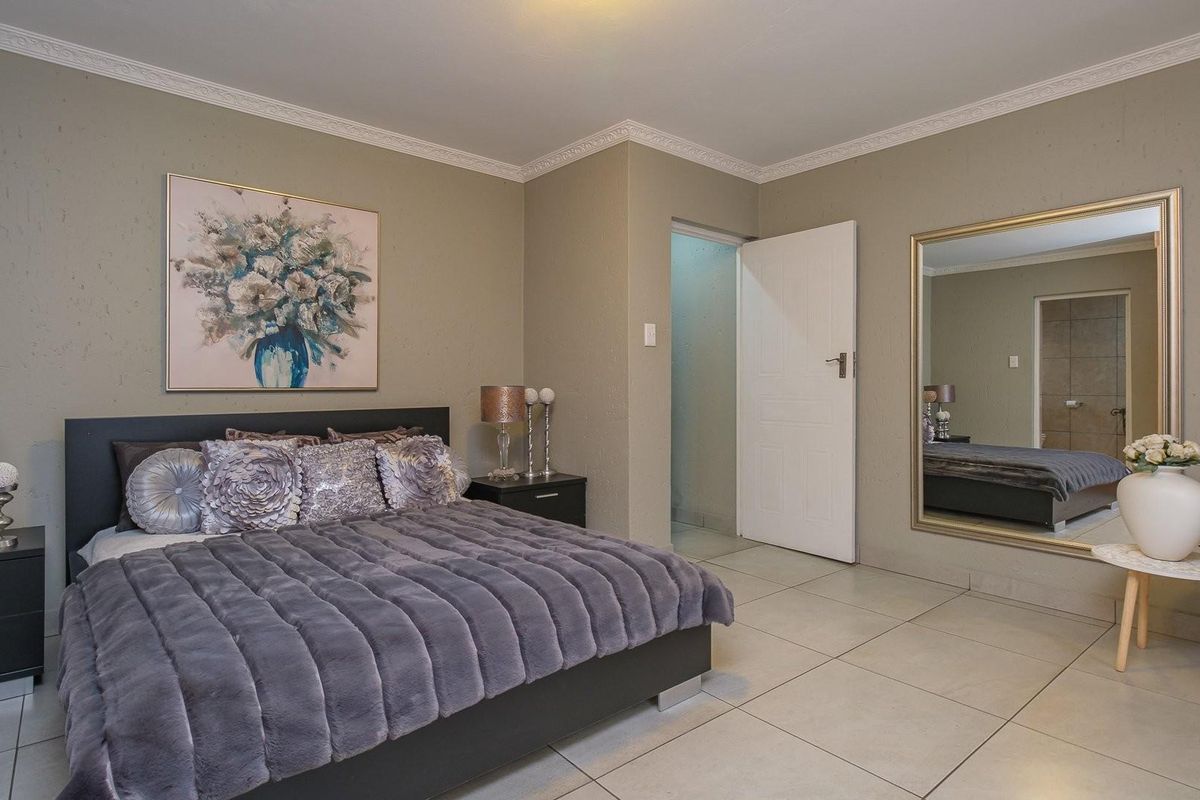 A well-maintained bedroom featuring neutral wall tones, tiled flooring, and decorative ceiling cornicing, providing a clean and comfortable living space.