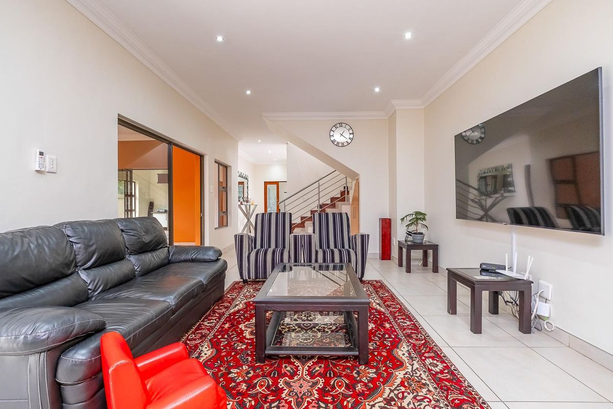 Spacious open-plan living area featuring tiled flooring, recessed downlighting, and a staircase with a metal balustrade.