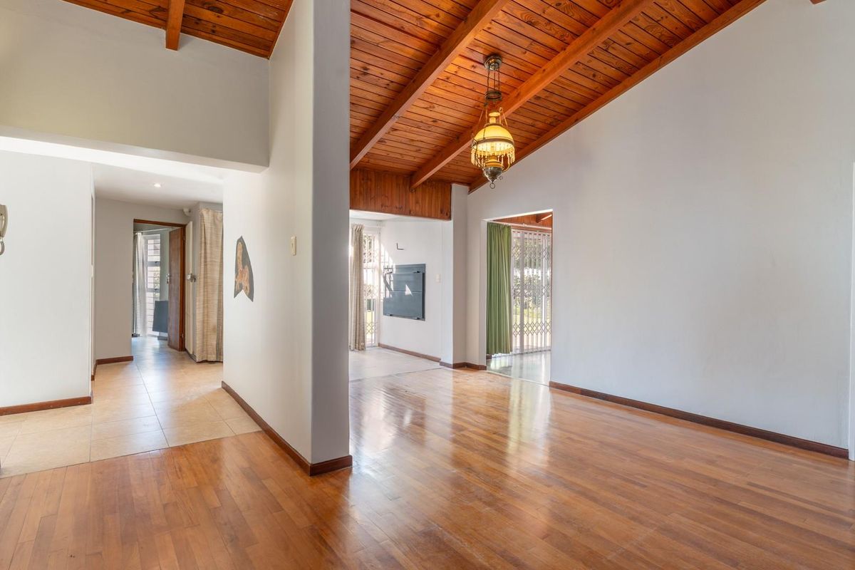 Spacious living area featuring high vaulted timber ceilings, exposed beams, and polished wooden flooring, creating an open and airy atmosphere.
