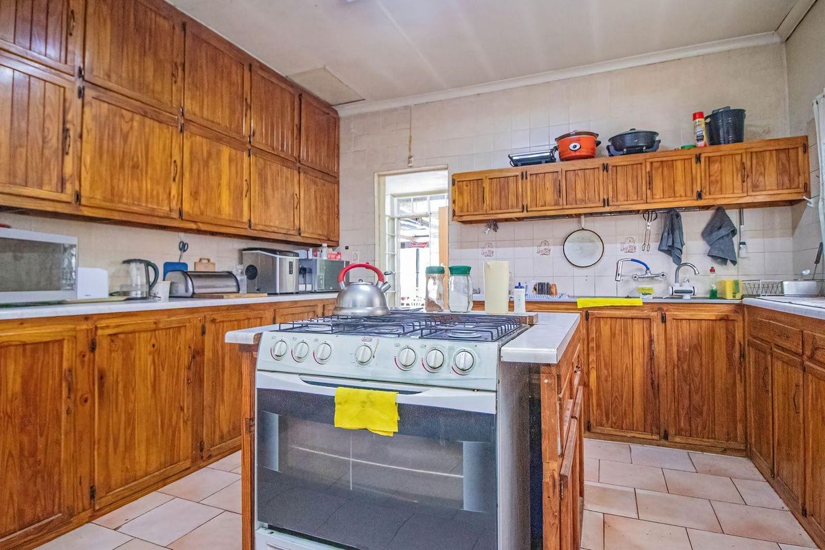 A traditional kitchen featuring extensive wooden cabinetry, a central gas stove island, and tiled flooring, offering a functional layout with ample storage space.