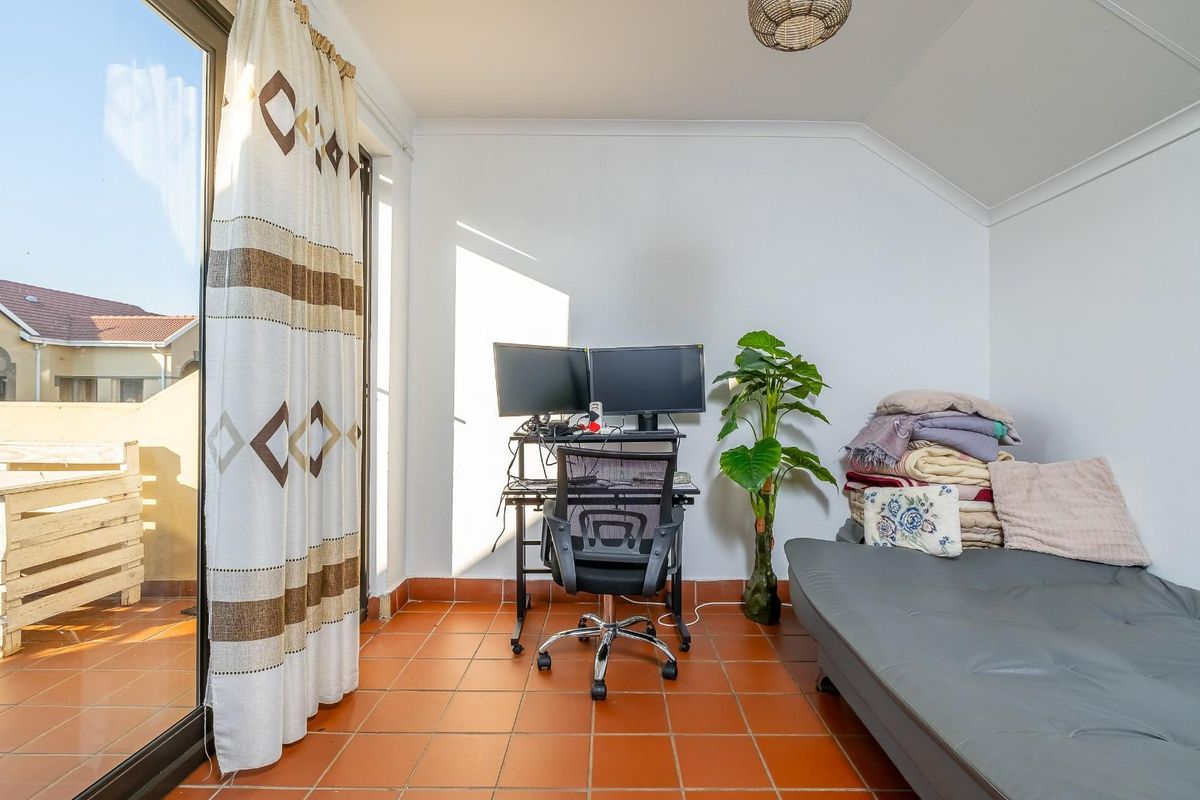 A bedroom featuring terracotta floor tiles and a large sliding glass door providing access to an outdoor balcony area.