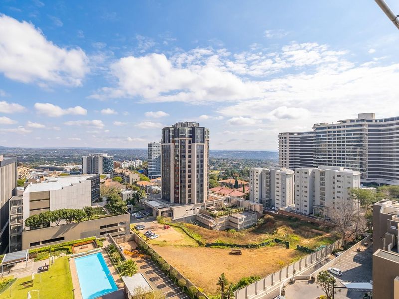 Elevated urban view overlooking the surrounding apartment complex, swimming pool area, and cityscape.