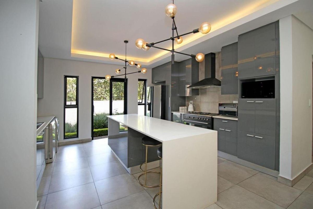 Modern kitchen featuring high-gloss grey cabinetry, a large central island with quartz countertops, integrated appliances, and stylish recessed ceiling lighting.
