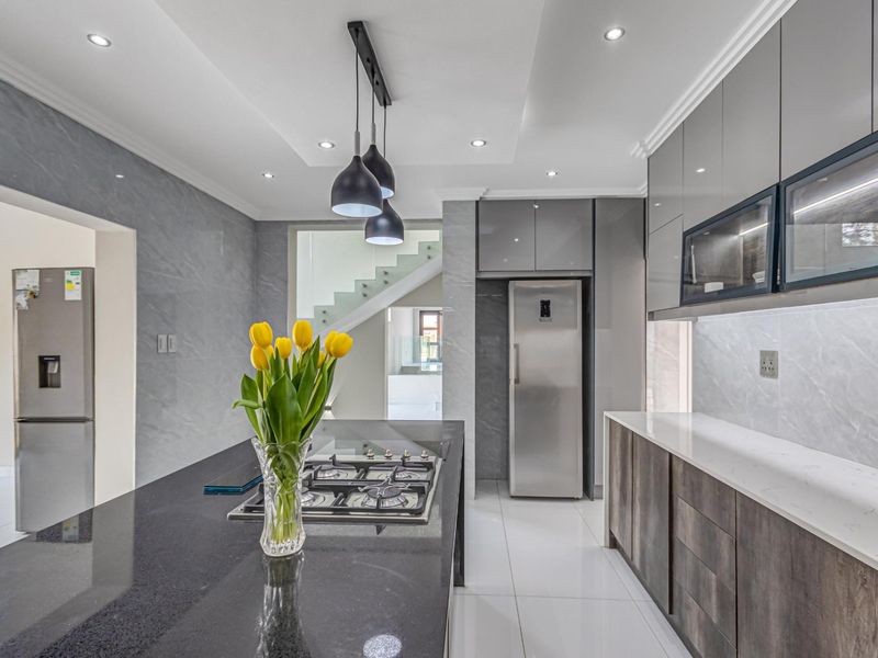 Modern kitchen featuring a central island with a gas hob, stone countertops, sleek cabinetry, and high-end finishes throughout.