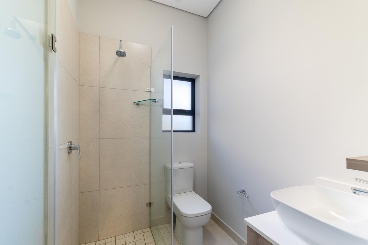 Modern bathroom featuring a glass-enclosed walk-in shower, contemporary vanity with a vessel sink, and a sleek toilet.