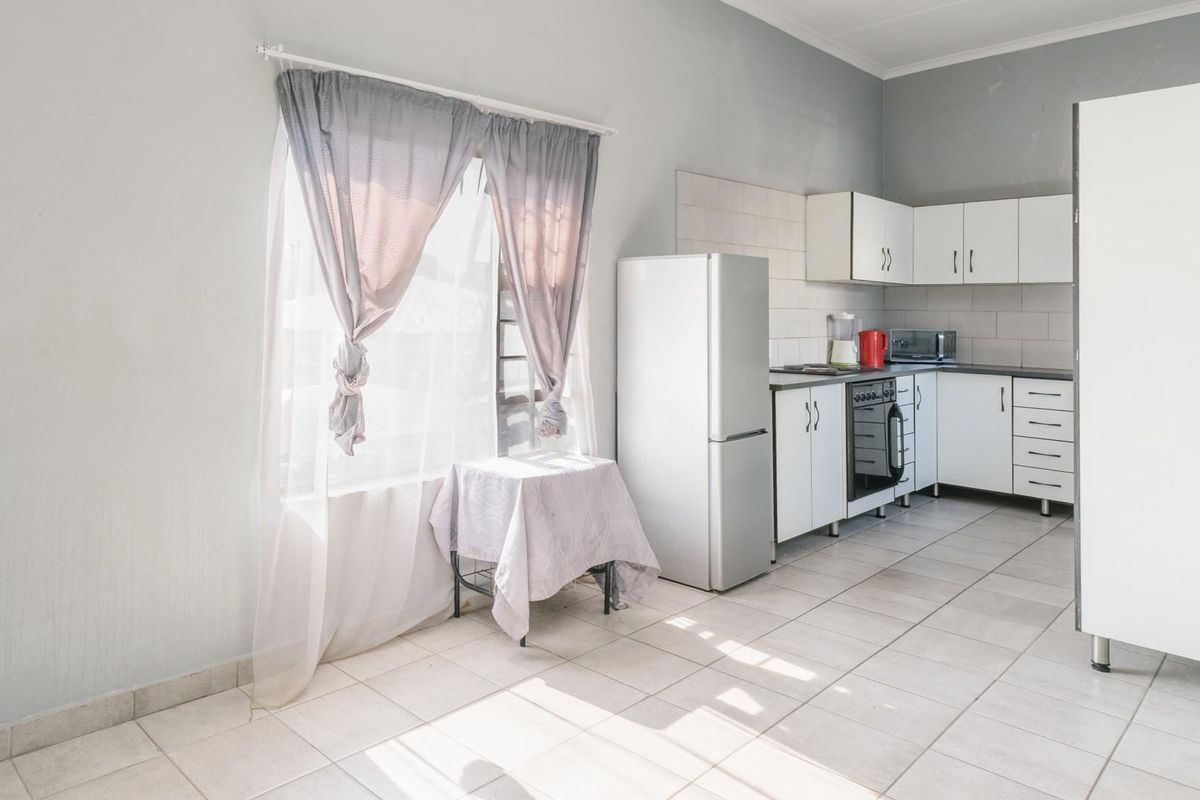 A functional kitchen featuring white cabinetry, tiled flooring, and built-in oven and hob, offering a clean and practical workspace.