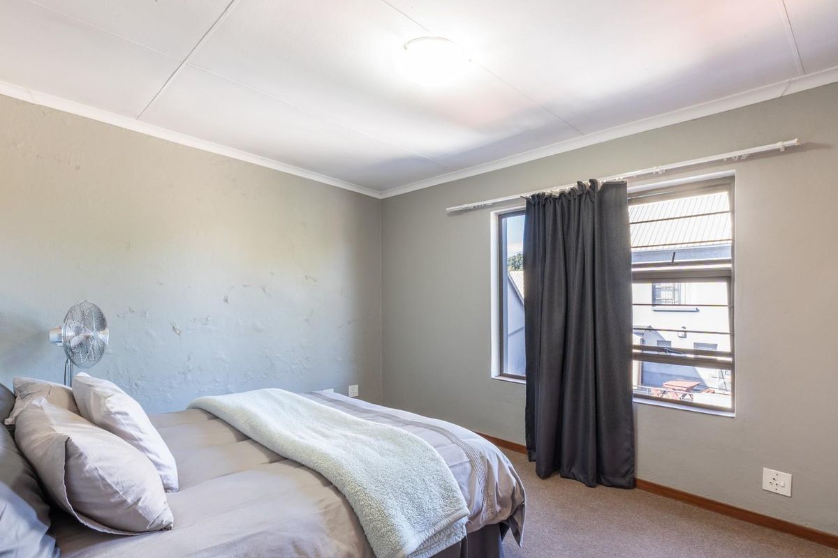 A bedroom featuring neutral-toned walls, carpeted flooring, and a window with curtain track, providing a functional and comfortable living space.
