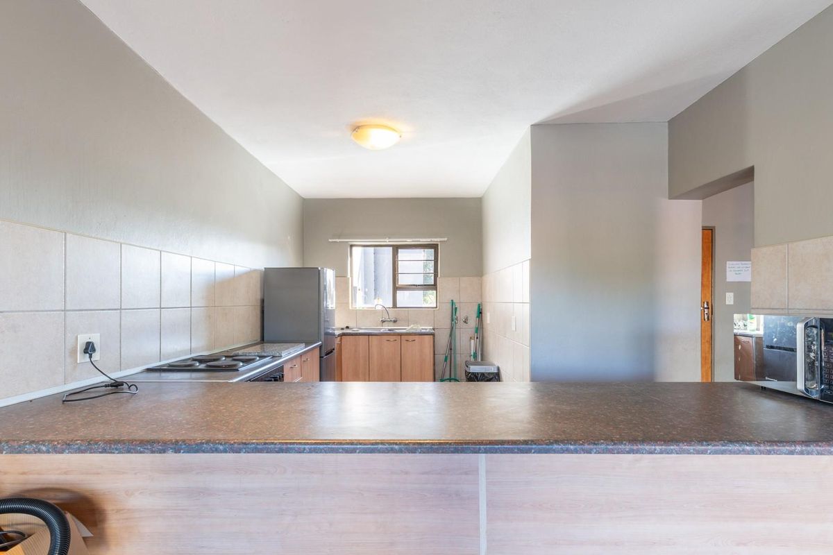 Functional kitchen featuring a breakfast bar, tiled backsplash, and built-in cabinetry with a sink and stove.