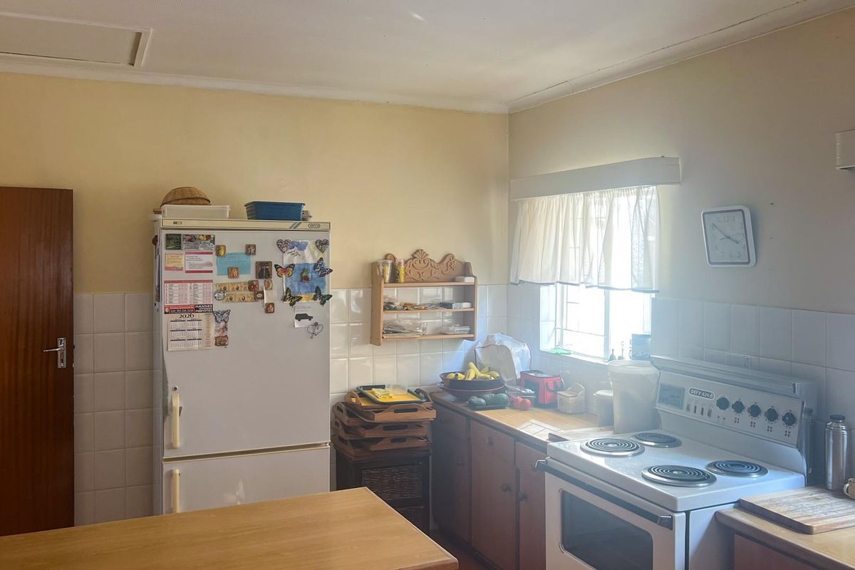 A functional kitchen featuring tiled splashbacks, wooden cabinetry, and a freestanding electric stove, offering a classic layout with natural light.