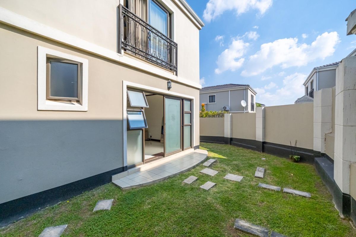 Rear view of the property featuring a small private garden, paved stepping stones, and a sliding door providing access to the interior.